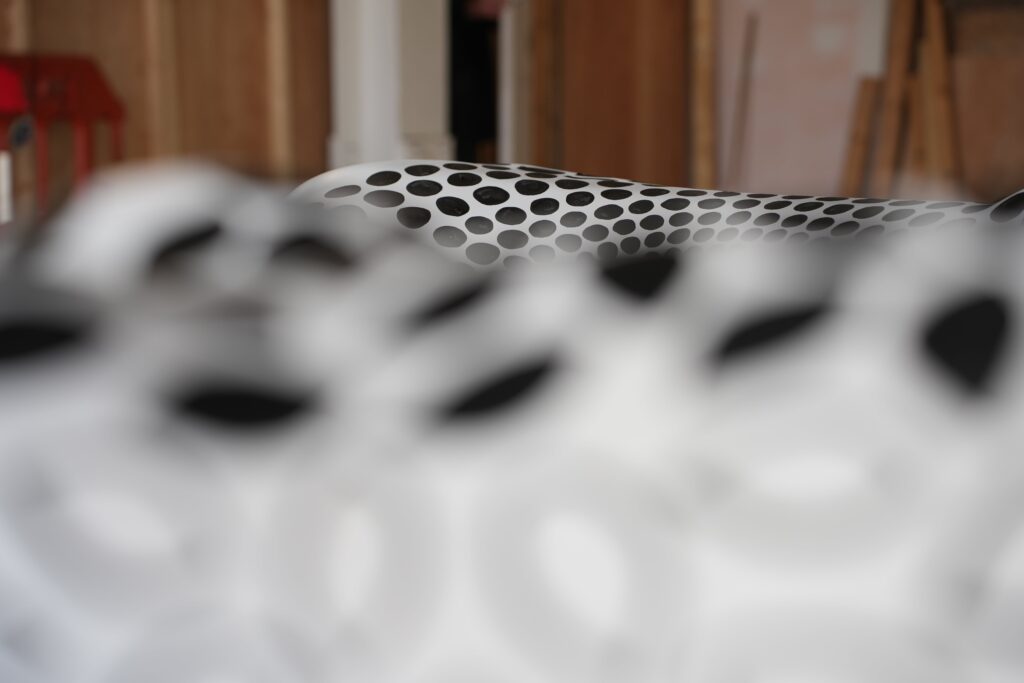 A camera close up on a sculpture which is covered in a monochrome, spot-light design. This is blurry in the foreground, with a similar design visible on a sculpture in the background.