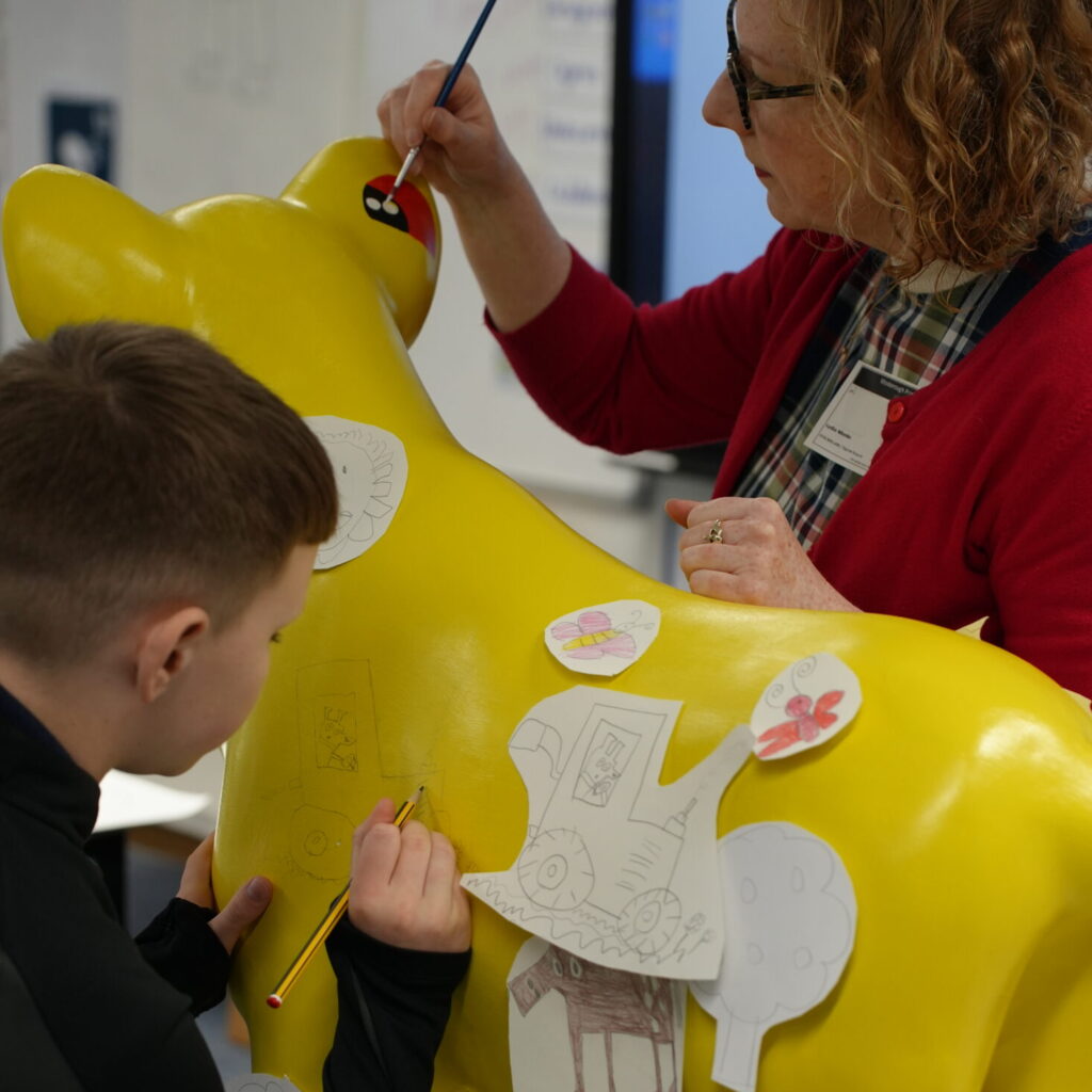 A pupil joins Lydia to start illustrating their school's cub