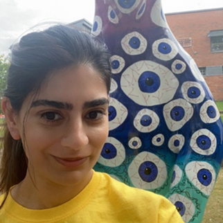 An image of a person taking a selfie. They are smiling at the camera and wearing a Sheffield Children's Hospital Charity t-shirt, and stood in front of a tall bear sculpture.