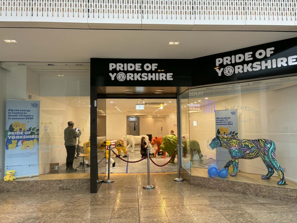 An image of a shop-front in Meadowhall Shopping Centre, in Sheffield. The logo above the door says 'Pride of Yorkshire' and inside, you can see artists working on their lion sculptures.