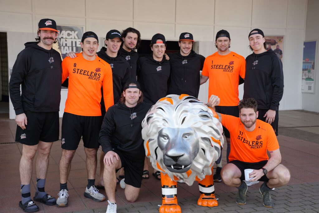 A team photograph of the Sheffield Steelers - 11 players - with a lion sculpture.