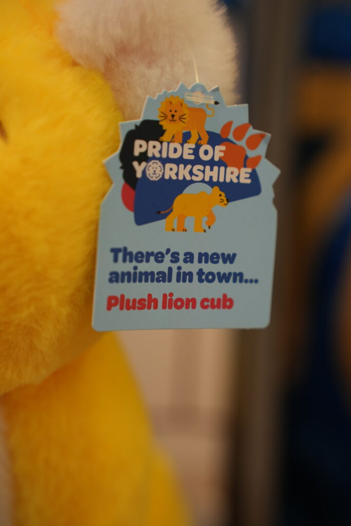 A close-up shot of a product swing tag on a yellow plush toy's ear.