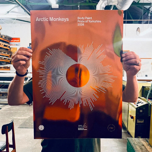 A photograph of someone holding up a metallic, copper print. It features the soundwaves of the Arctic Monkeys song, Body Paint.